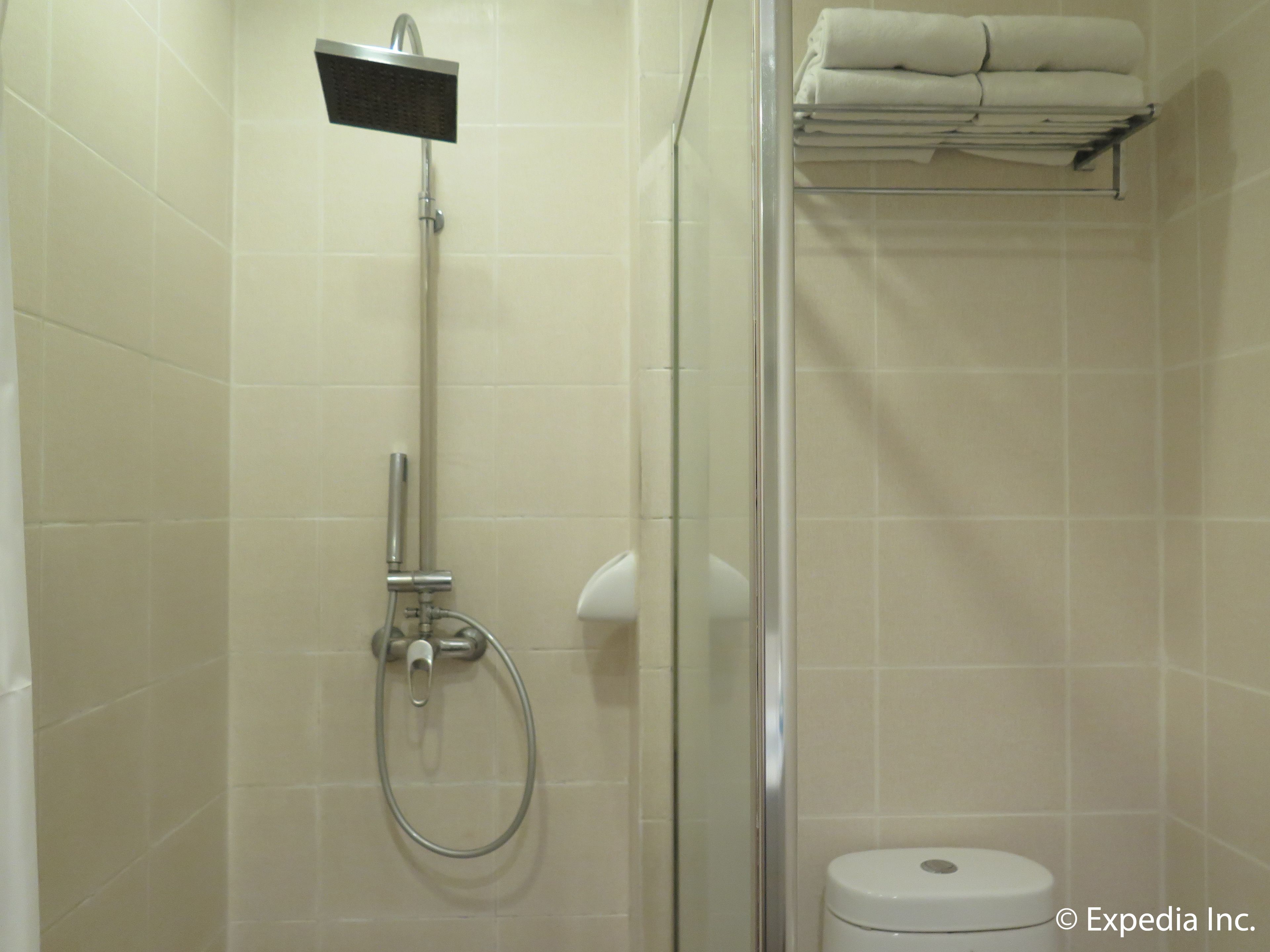 A shower with a handheld showerhead, a glass-enclosed shower area, and a toilet with a towel rack above it.