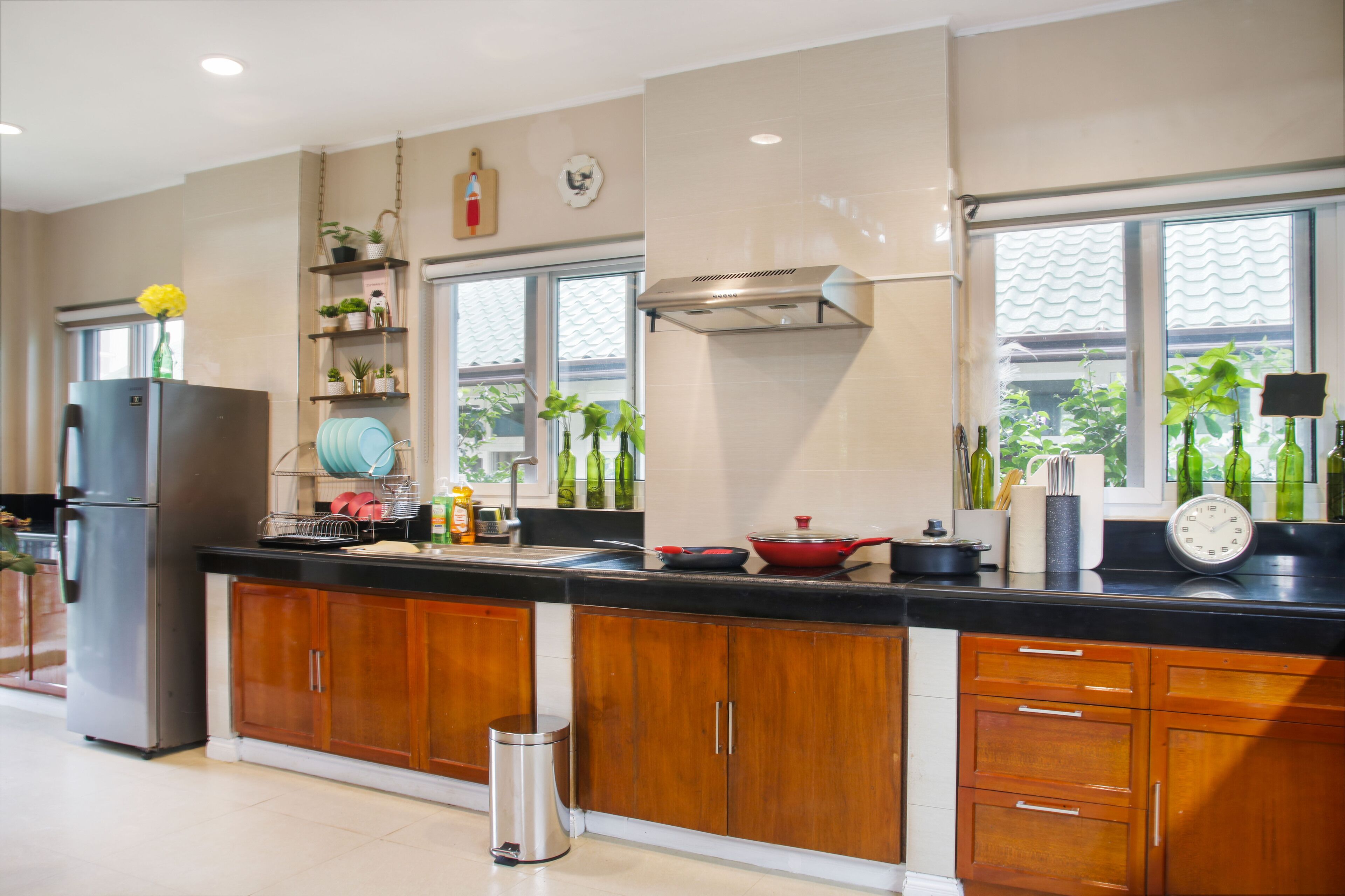 A modern kitchen with wooden cabinets, a stainless steel refrigerator, and a black countertop.