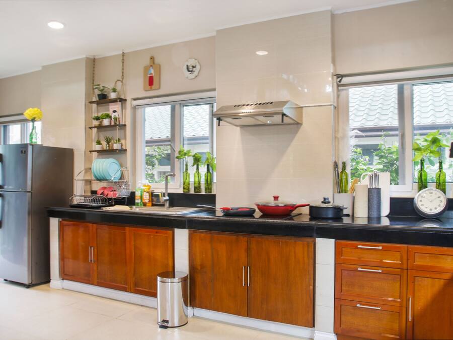 A modern kitchen with wooden cabinets, a stainless steel refrigerator, and a black countertop.