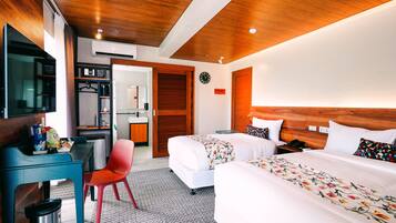 Habitació d'hotel amb sostre de fusta, escriptori amb cadira, llit amb roba de llit floral i una petita taula de nit.