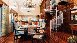 A spacious dining area with a wooden table and chairs, a chandelier, and a spiral staircase. - Hotel Kimberly Tagaytay (Tagaytay)