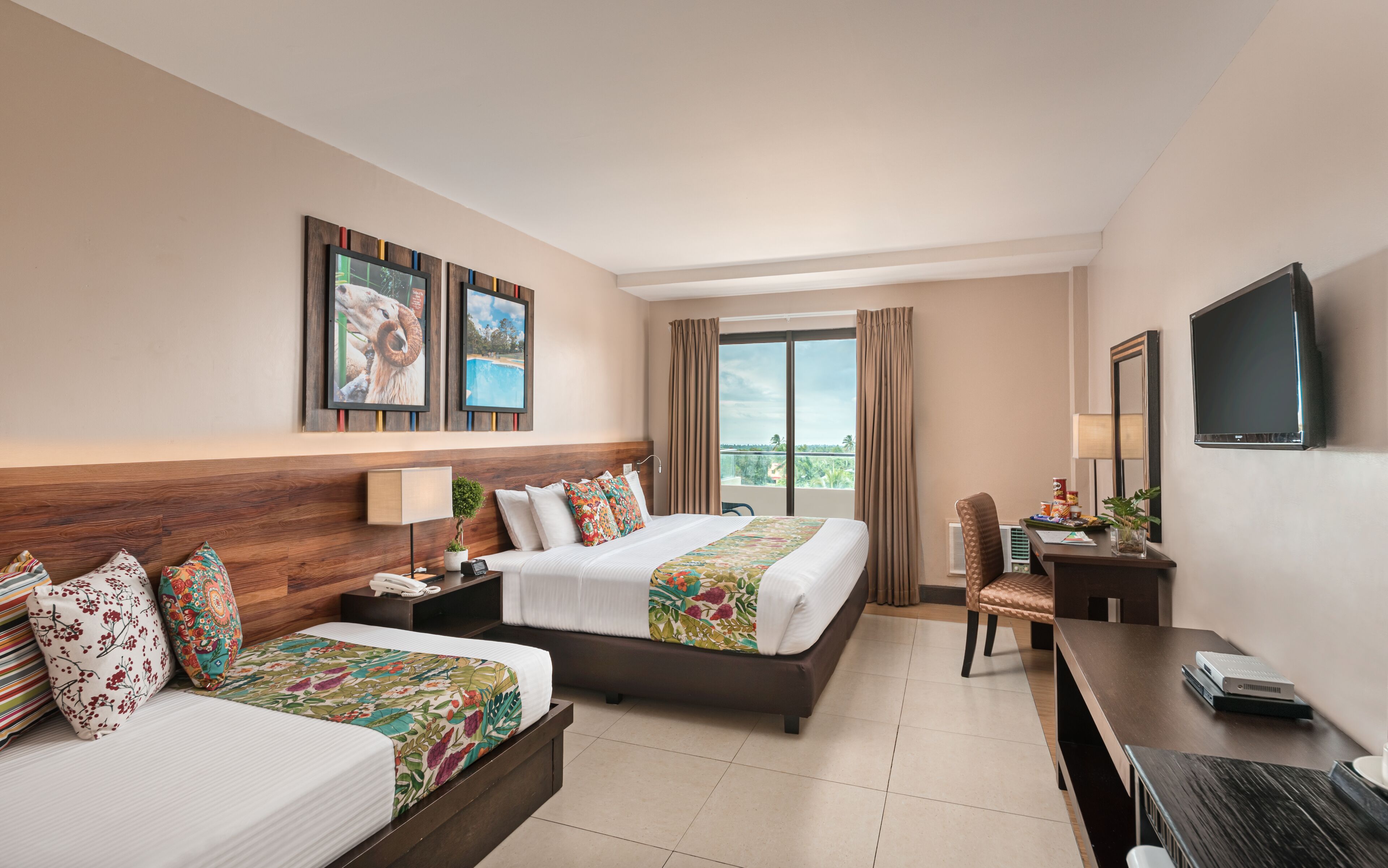 A hotel room with a bed, a desk, a chair, a TV, and a window with curtains.