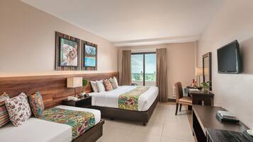 A hotel room with a bed, a desk, a chair, a TV, and a window with curtains.