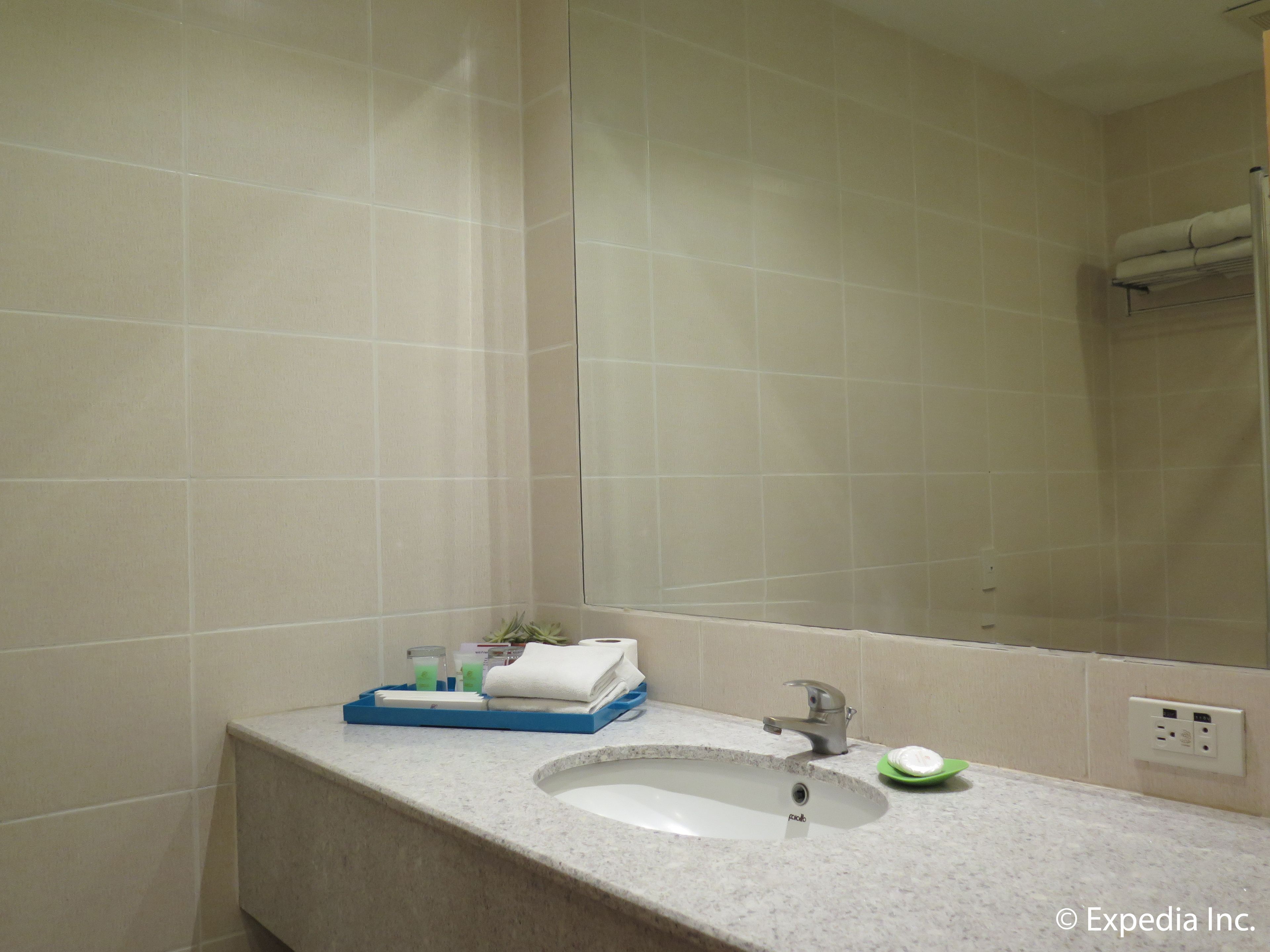 A bathroom with a sink, mirror, and toiletries.