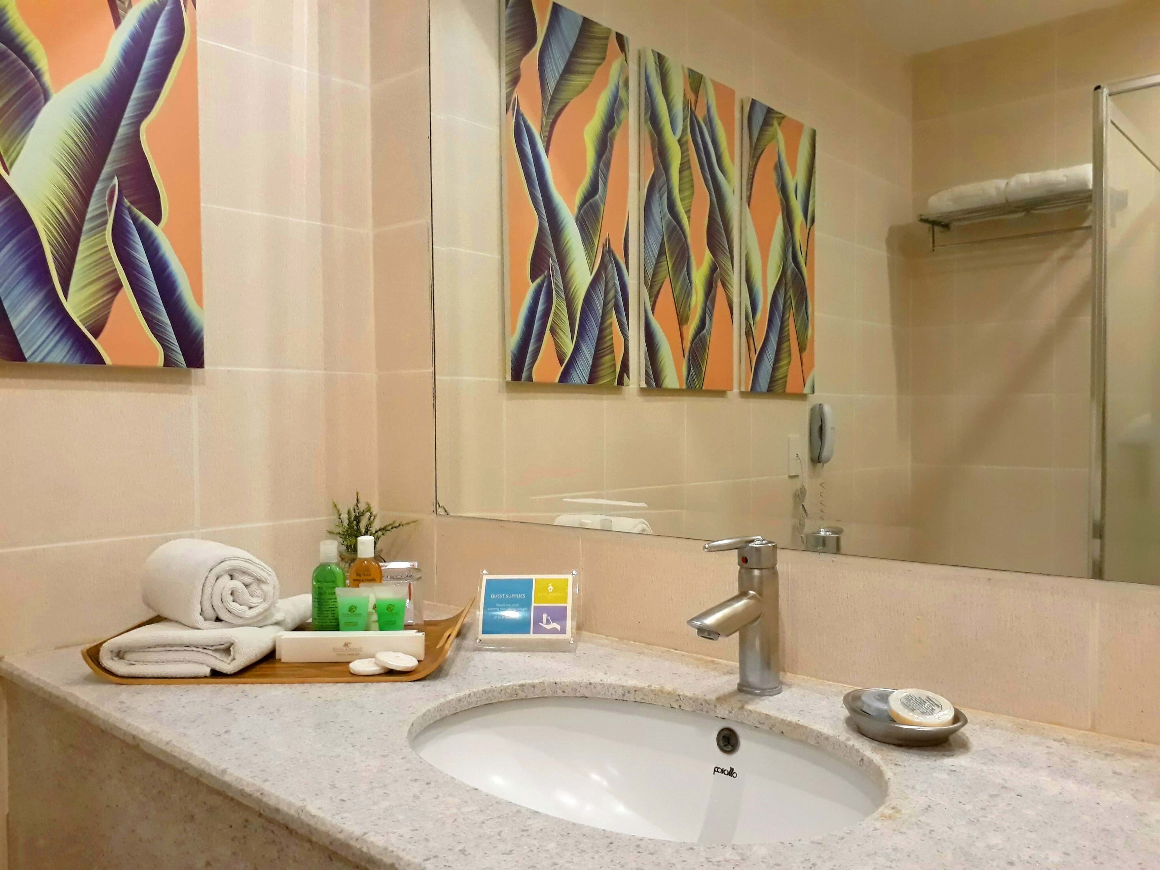 Un baño con lavamanos, espejo, toallero y un panel de amenities para huéspedes.