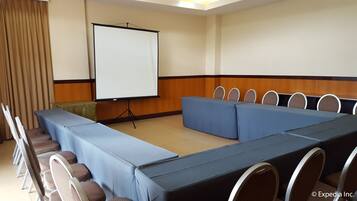 A conference room with a long table, chairs, a projector screen, and a podium.