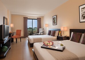 A hotel room with two beds, a TV, a chair, a balcony with curtains, and a tray with breakfast items. - Hotel Kimberly Tagaytay (Tagaytay)