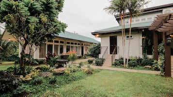 A building with a green roof, surrounded by a well-maintained garden with various plants and a pathway leading to the entrance.