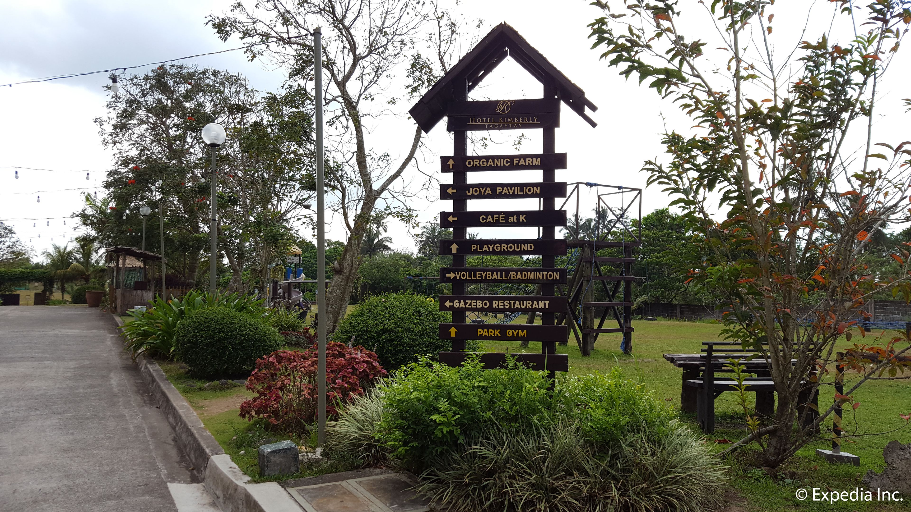 A wooden signpost with directions to various amenities including a playground, volleyball/badminton court, and park gym.