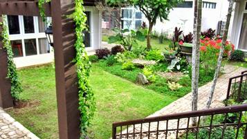 A well-maintained garden with a stone pathway, a pergola with climbing plants, and a variety of shrubs and flowers.