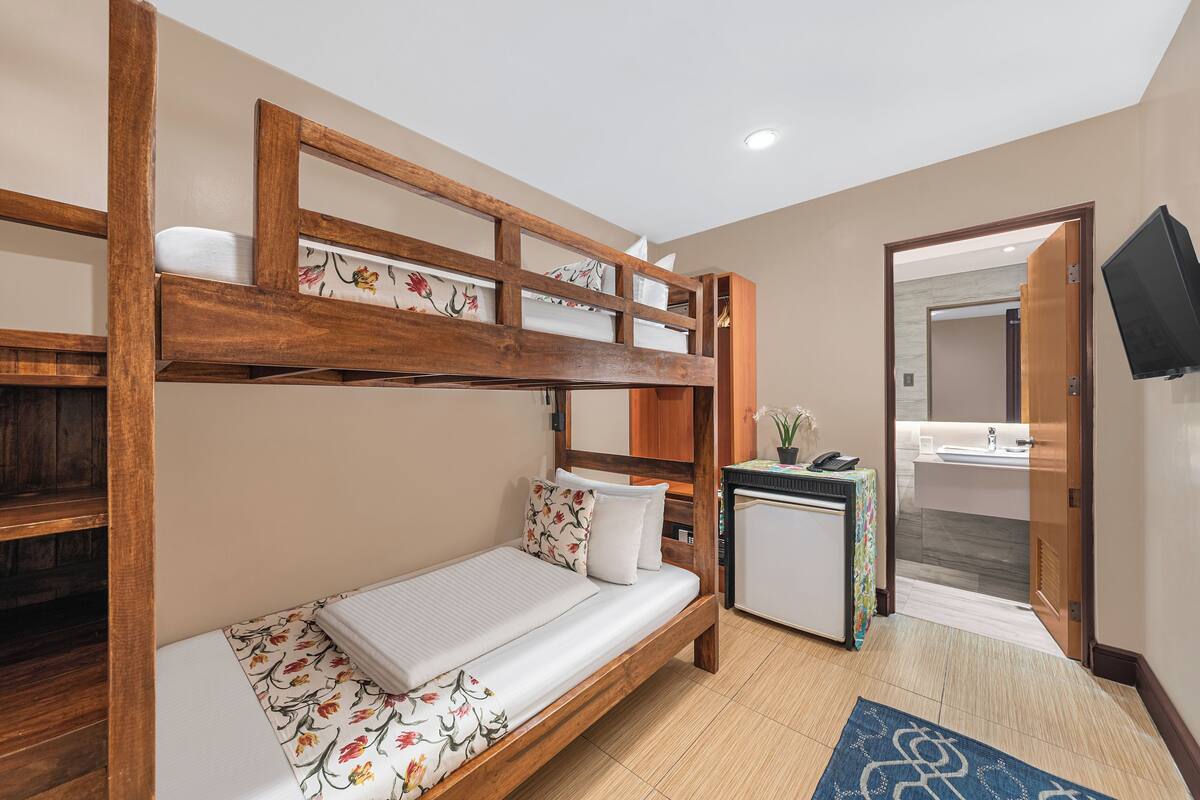 Un lit superposé avec un bureau et une petite salle de bain dans la chambre.