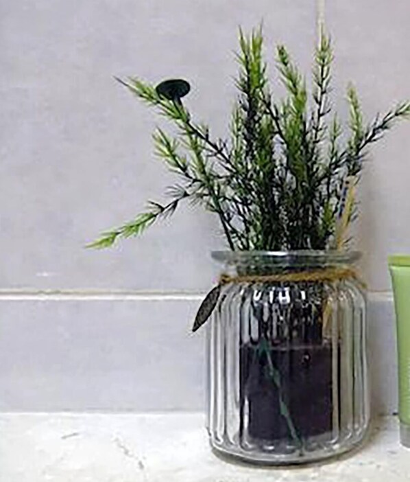 A glass jar with a plant, tied with a string, placed on a tiled surface. - Hotel Kimberly Manila (Manila)
