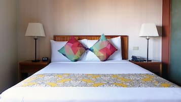 Une chambre d’hôtel avec un lit, deux tables de chevet, une lampe de chaque côté et une couvre-lit à motifs.