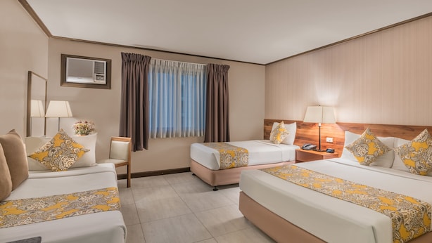 A hotel room with two beds, a nightstand, a lamp, a window with curtains, and a wall-mounted air conditioner. - Hotel Kimberly Manila (Manila)