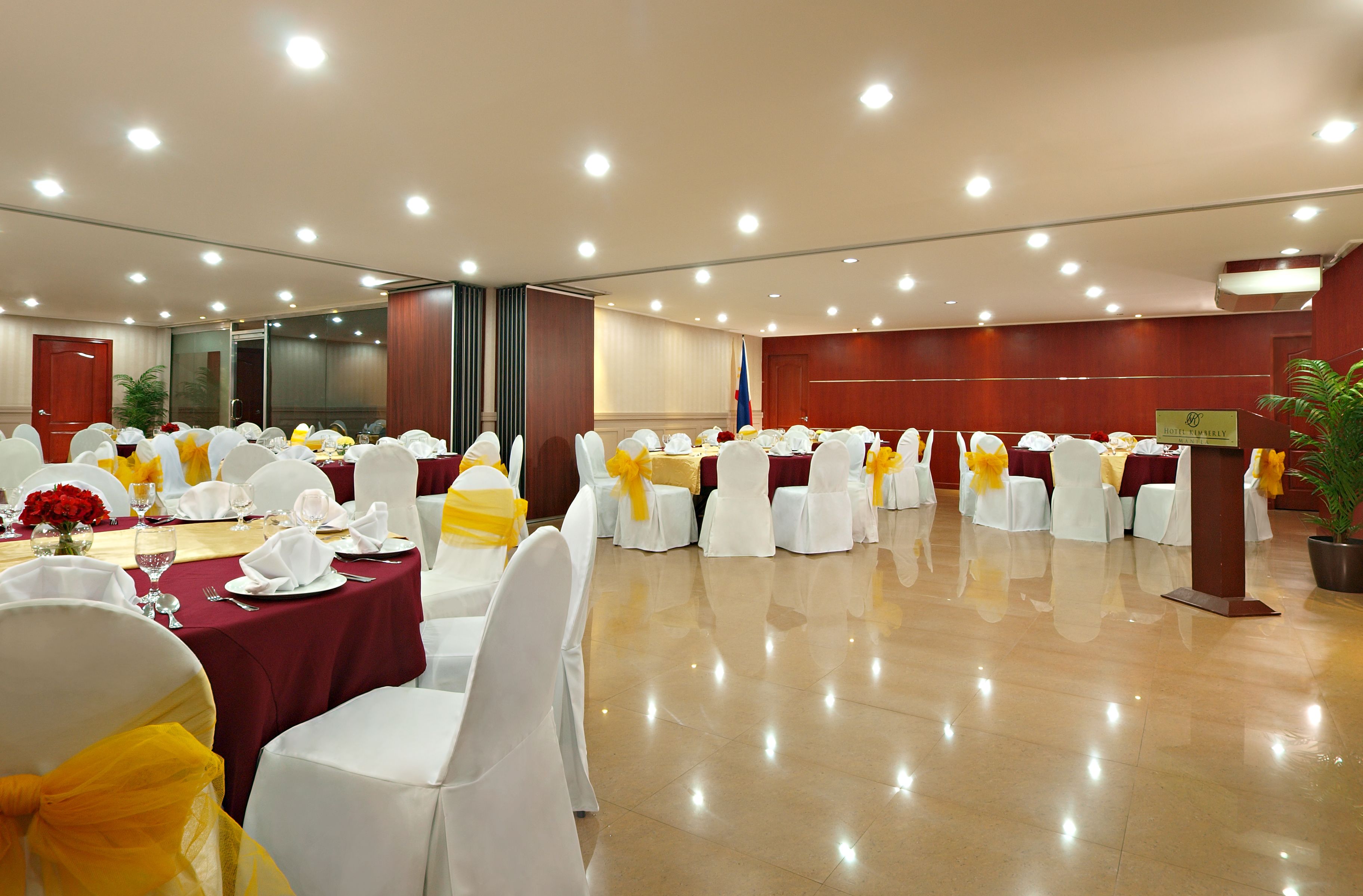 A banquet hall with round tables, white chairs, and yellow sashes.
