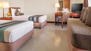Habitación de hotel con dos camas, un escritorio con computadora, televisión y sofá.