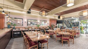 A restaurant with wooden tables and chairs, a buffet area, and a staircase leading to an upper level. - Hotel Kimberly Manila (Manila)