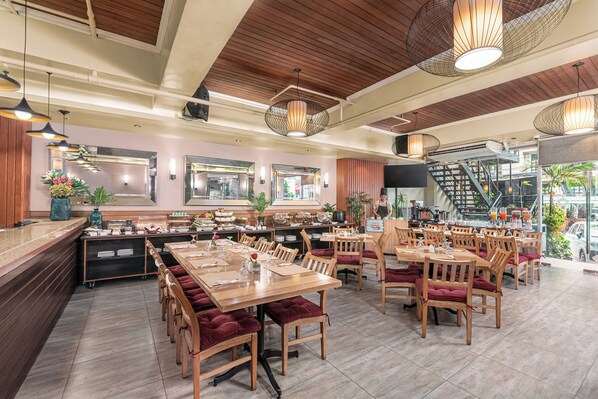 A restaurant with wooden tables and chairs, a buffet area, and a staircase leading to an upper level.