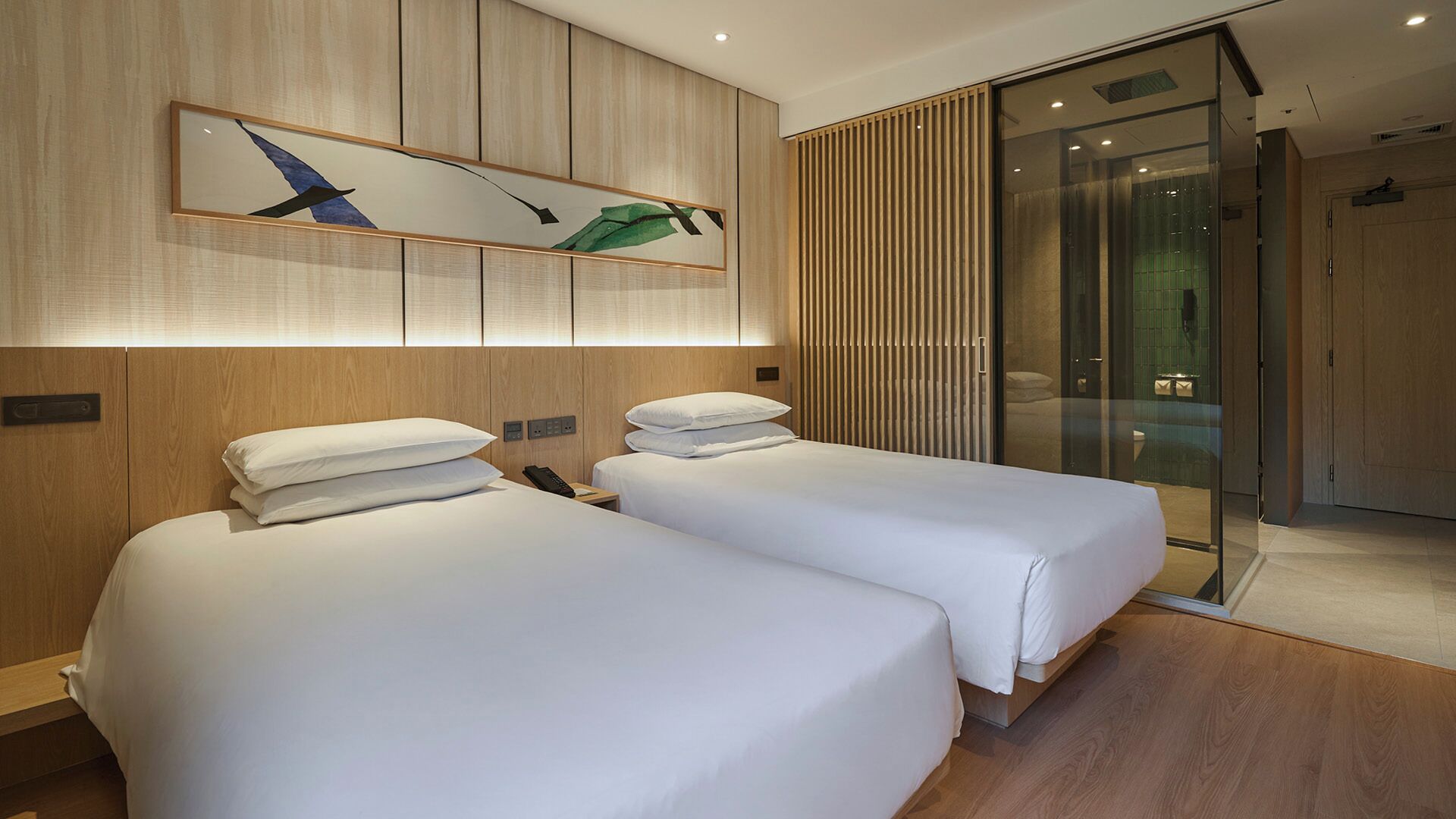Habitació d'hotel amb dos llits, una finestra gran i un disseny modern.
