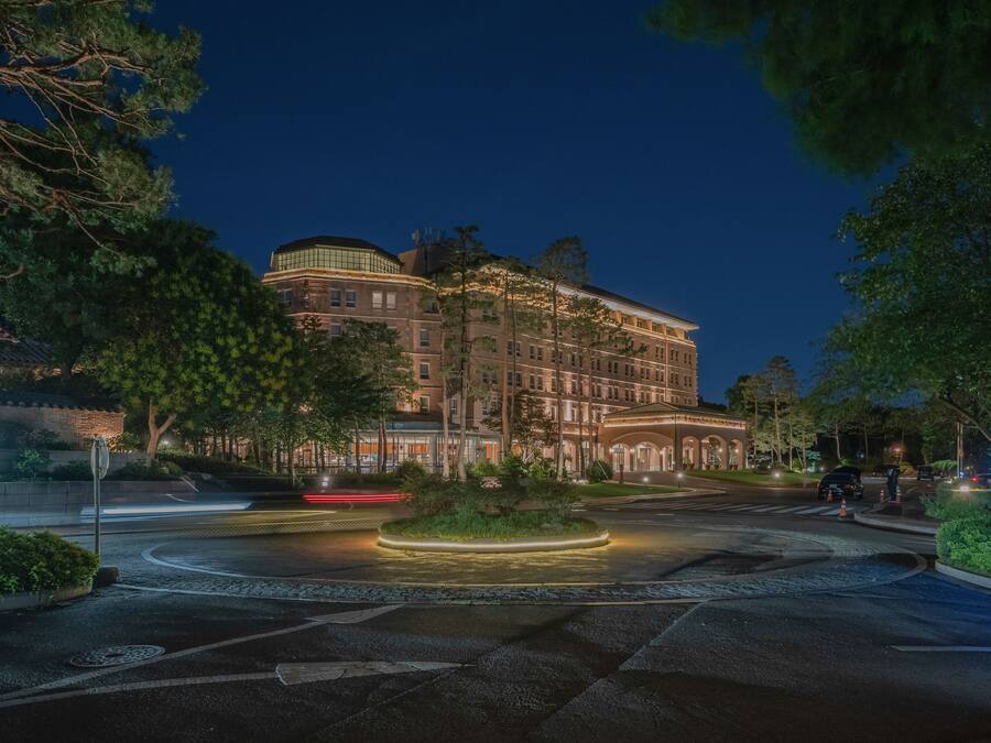 Ein gut beleuchtetes Hotel mit Kreisverkehr, Grünflächen und einem Parkschild.
