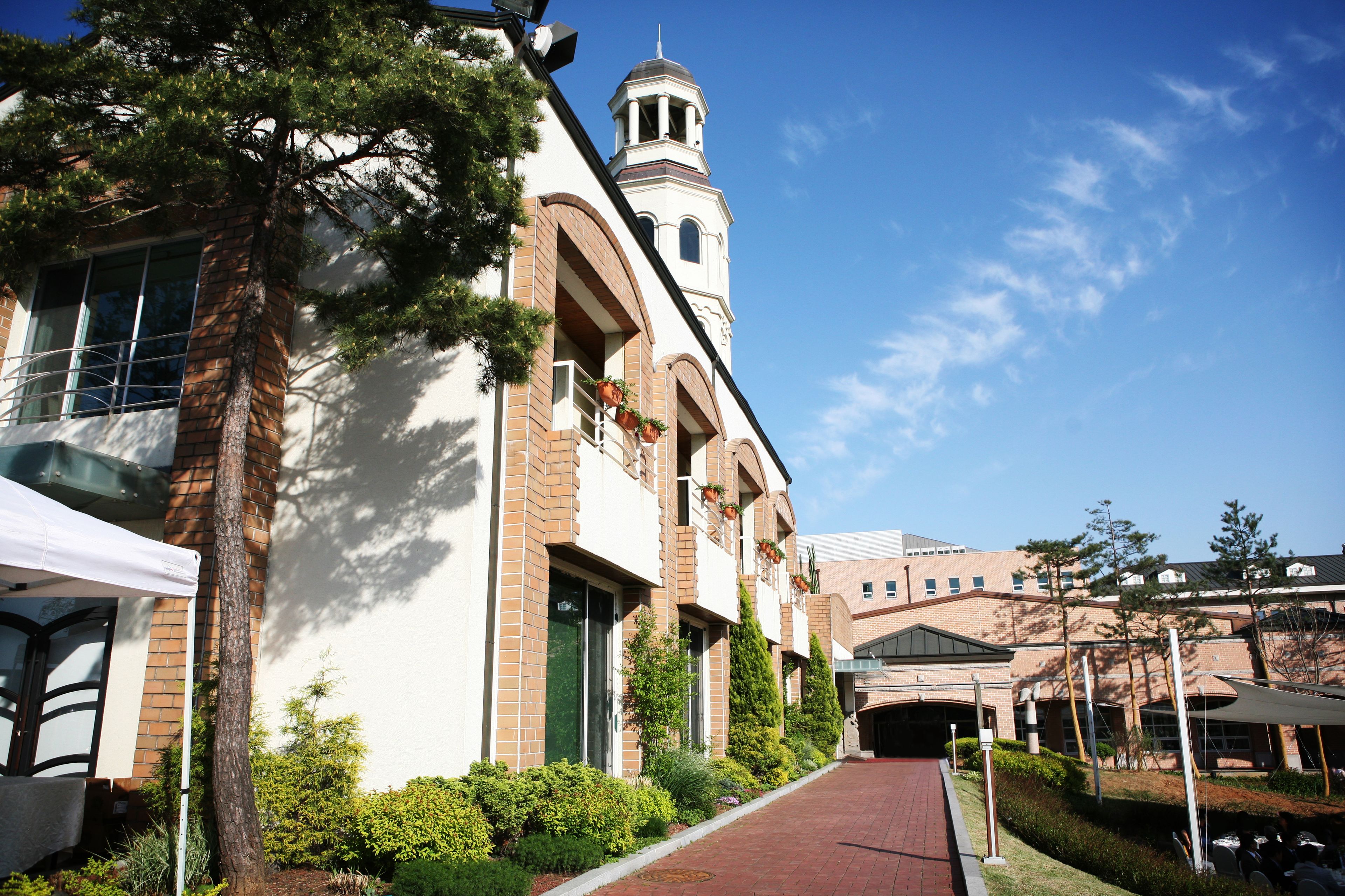 A building with a tower, a covered walkway, and a brick facade.