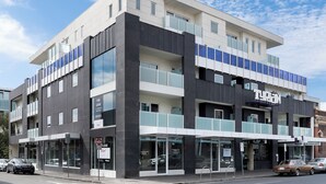 Un edificio moderno con un letrero de 'For Lease', ventanas grandes y un letrero de 'Tyrone' que indica un negocio en la planta baja.