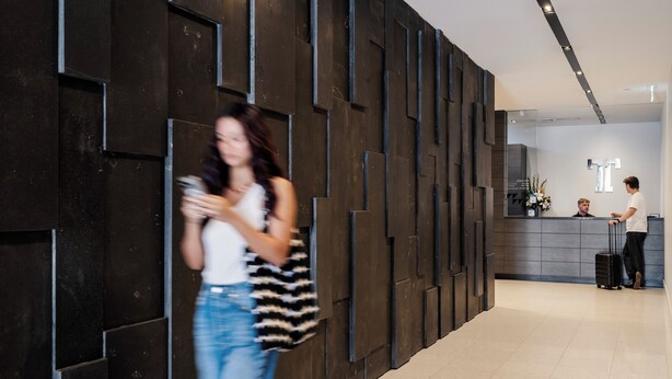 Un moderno vestíbulo de hotel con mostrador de recepción, una pared grande con patrones geométricos y un suelo de baldosas limpio.