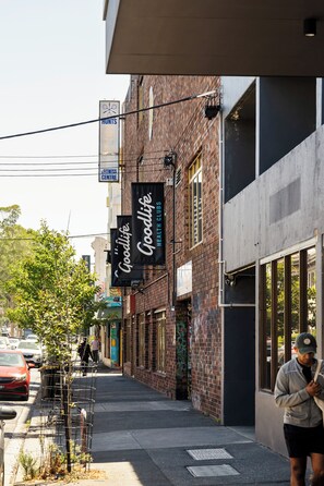 Una calle con un edificio que muestra un letrero de 'Goodlife Health Clubs' y un aviso de 'Fitness Centre'.