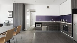 Una cocina moderna con armarios oscuros, microondas integrado y refrigerador de acero inoxidable.