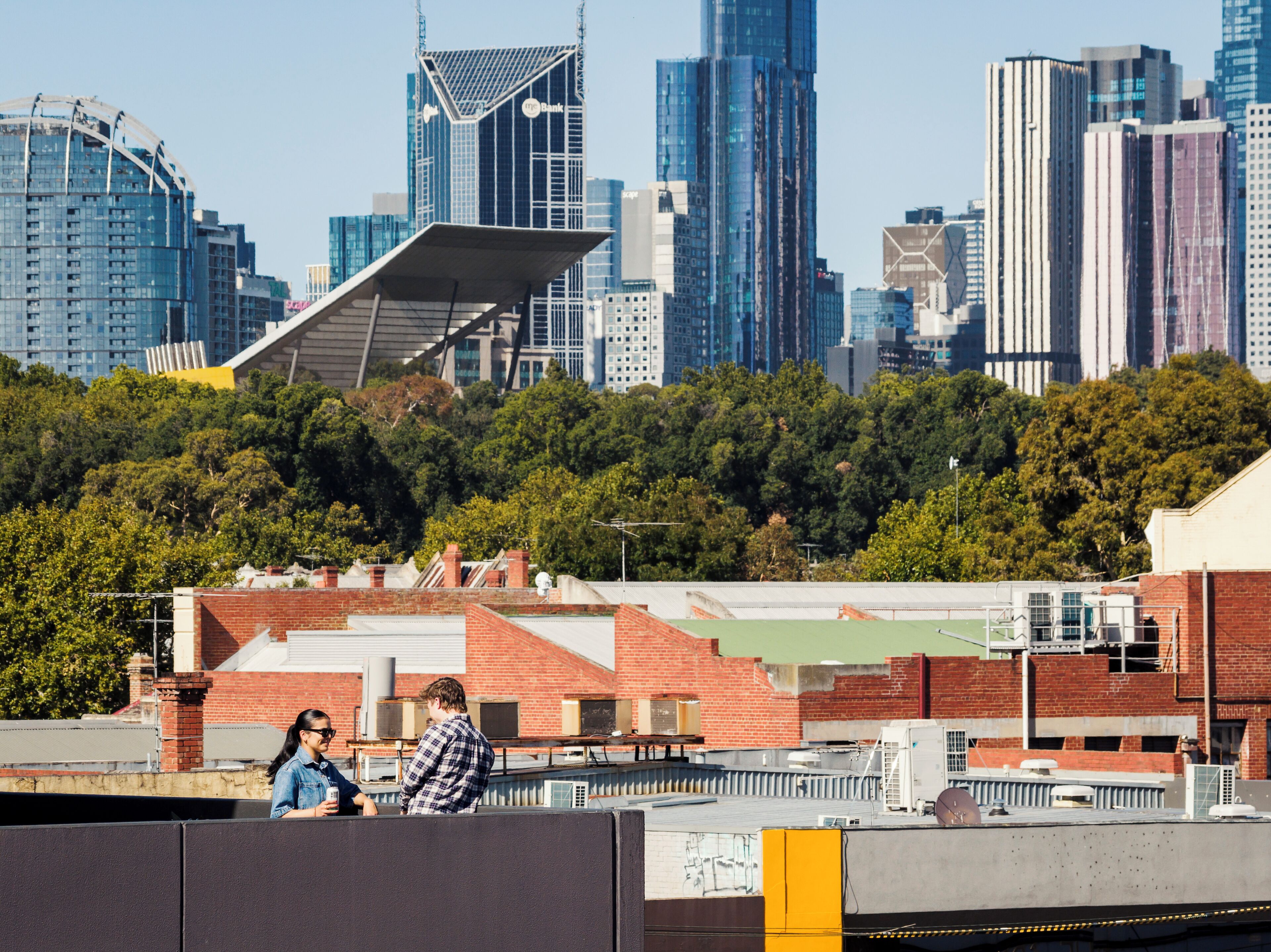 A city skyline with modern buildings and a large green park in the foreground.