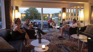 A modern lounge area with leather sofas, round tables, and ambient lighting. - Hotel Pejsegården (Braedstrup)