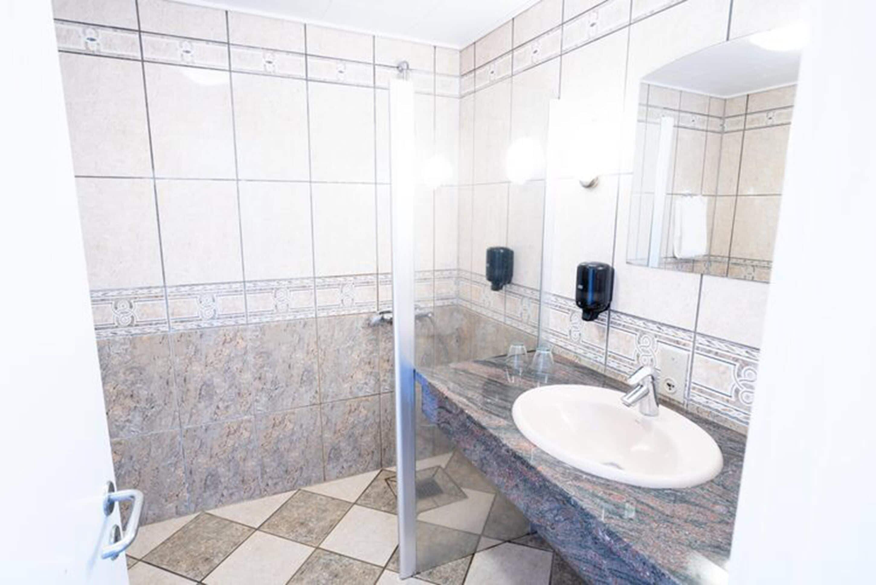 Un baño con cabina de ducha de vidrio, lavamanos de mármol y espejo.