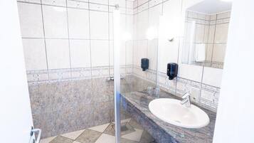 Un baño con cabina de ducha de vidrio, lavamanos de mármol y espejo.