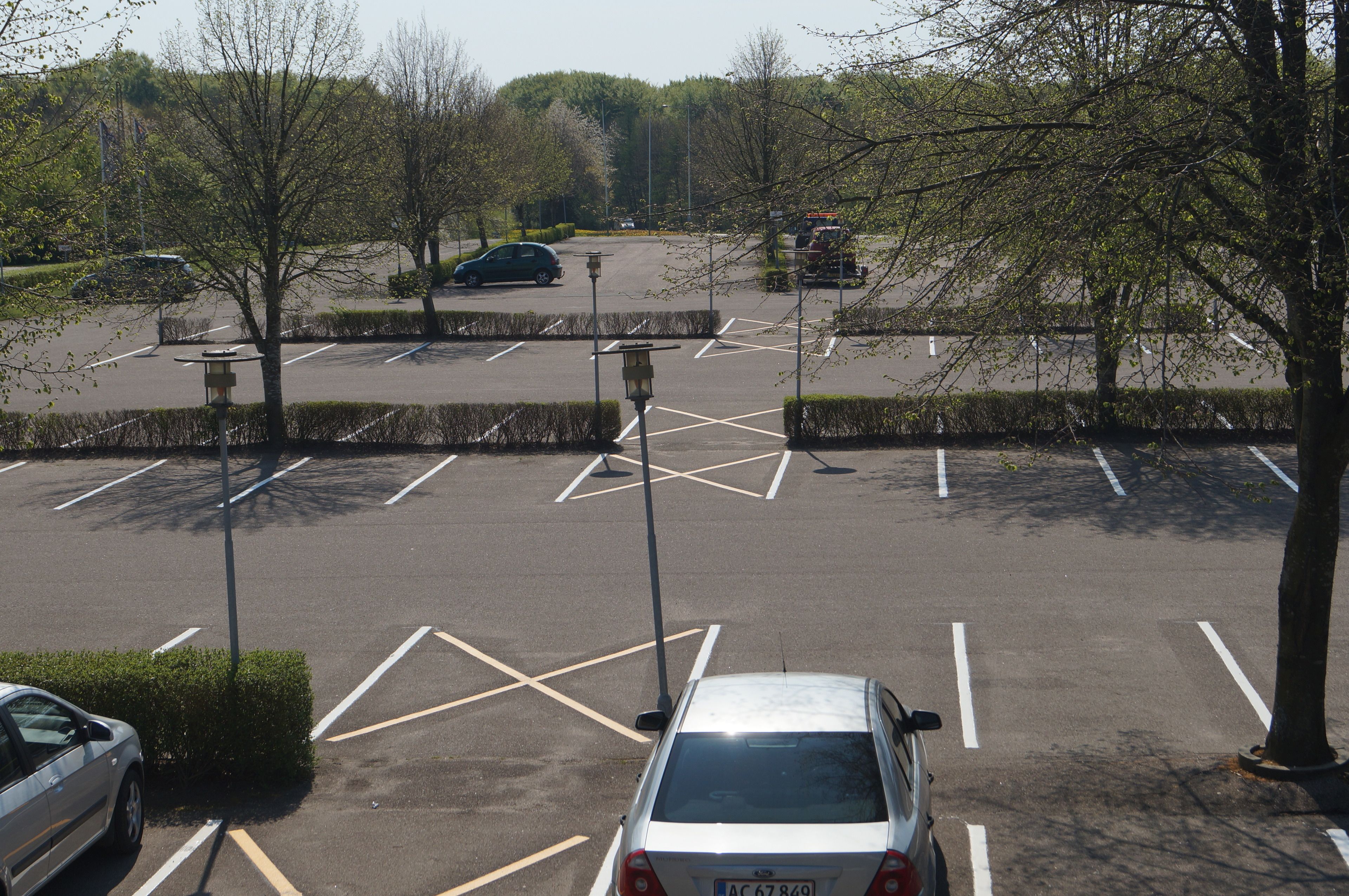 Ein Parkplatz mit markierten Stellplätzen und einigen Autos.
