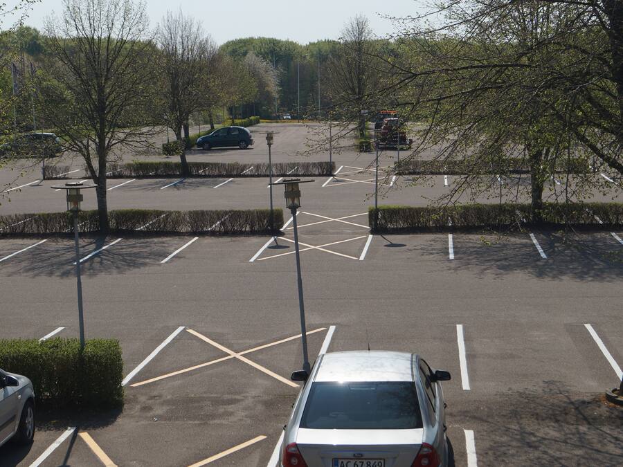 Um estacionamento com vagas demarcadas e alguns carros.