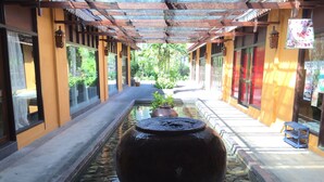A corridor with a large water feature, potted plants, and traditional architecture. - Villa Molek (Langkawi)