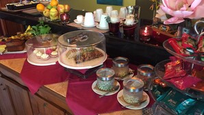 A buffet setup with various food items, including fruits, pastries, and desserts, arranged on a counter with a red cloth. - Villa Molek (Langkawi)