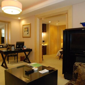 Une chambre d’hôtel équipée d’une télévision à écran plat, d’un bureau avec un ordinateur, d’une table basse et d’un canapé.