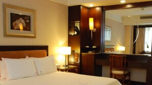 Habitación de hotel con una cama grande, un escritorio, una silla y un espejo.