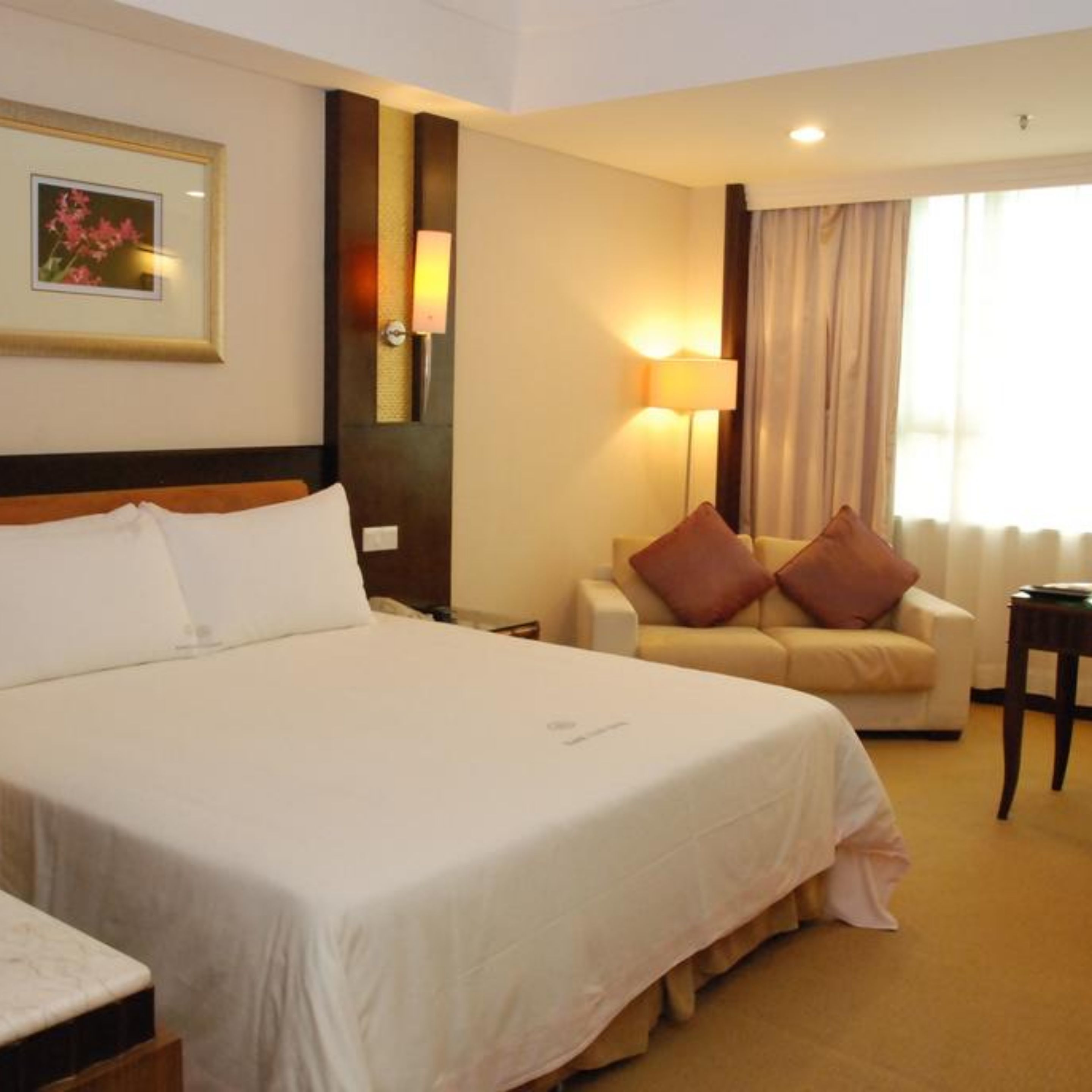 Una habitación de hotel con una cama grande, un sofá, una mesita y una lámpara.