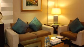 Habitación de hotel con un sofá, una mesa de centro, una lámpara y un cuadro en la pared.
