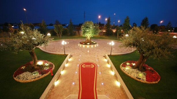 A well-lit garden pathway leading to a central tree, surrounded by evenly spaced lights and flower beds. - Grand Hotel del Parco - Bergamo Airport (Stezzano)
