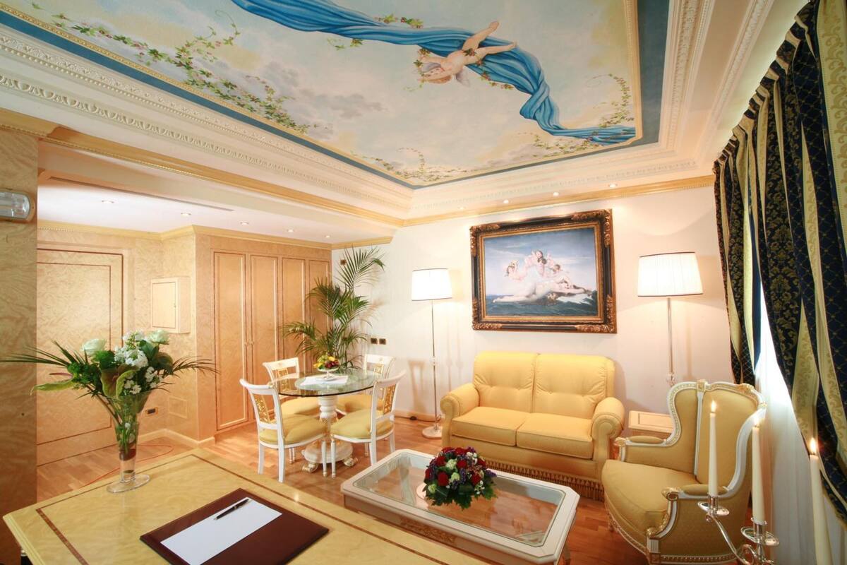 Una habitación lujosa con comedor, un sofá, una silla y un cuadro en la pared.