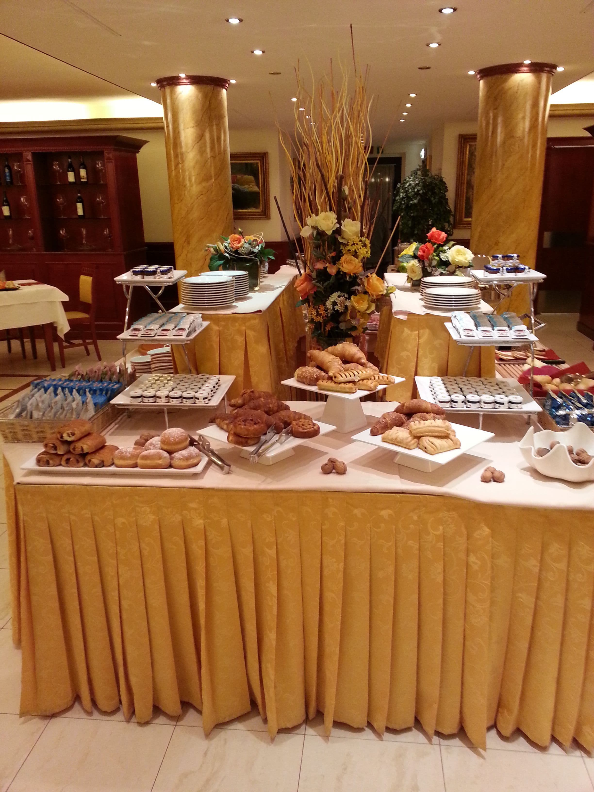 A buffet table with various food items and a floral centerpiece.