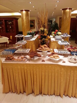 A buffet table with various food items and a floral centerpiece. - Grand Hotel del Parco - Bergamo Airport (Stezzano)