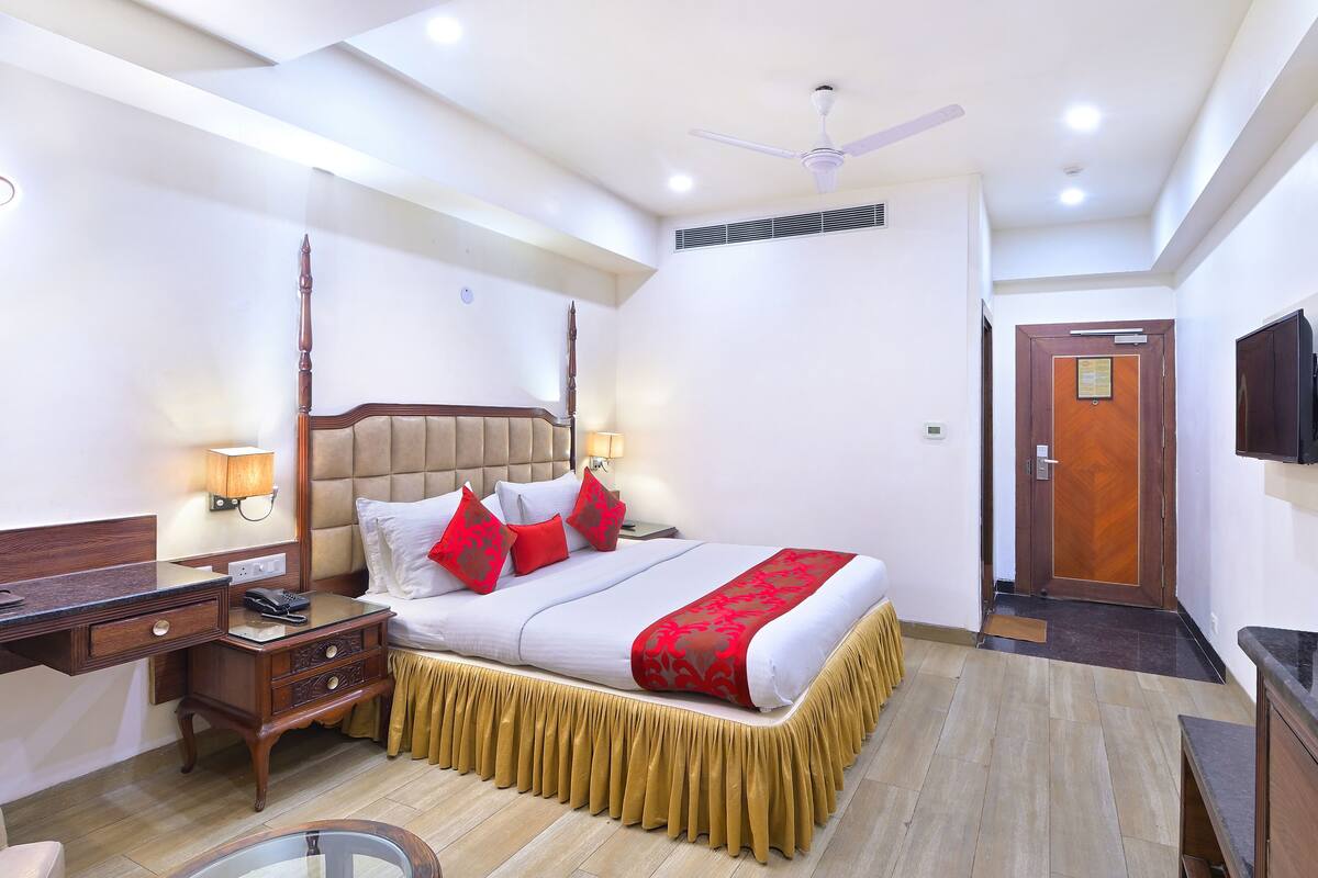 A hotel room with a bed, bedside table, lamp, and a ceiling fan.