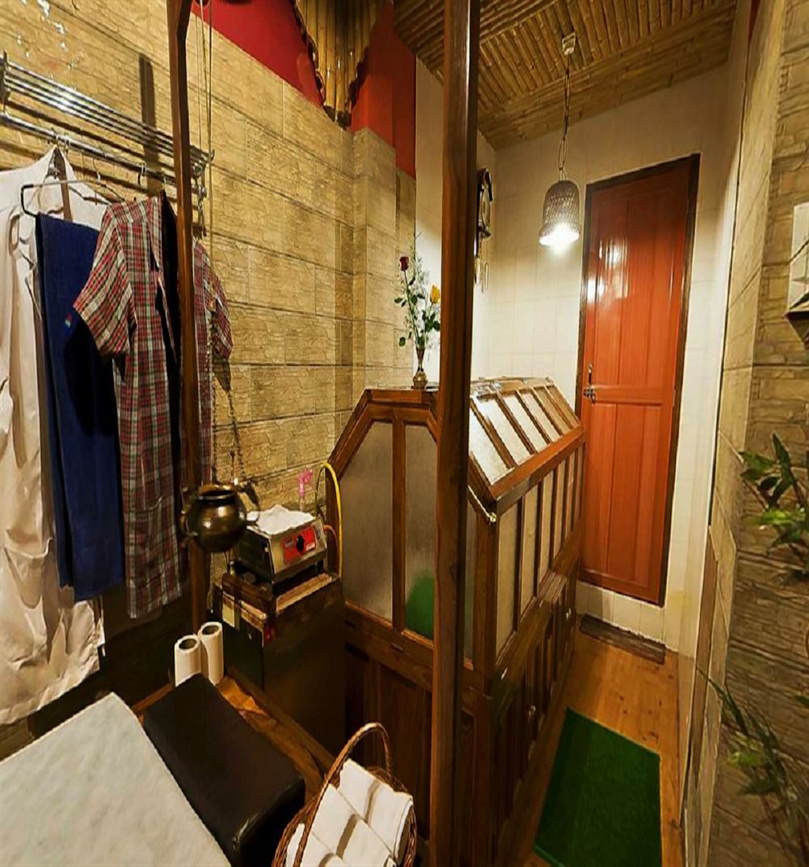A small, cozy room with a wooden bench, a small table with a vase of flowers, and a wooden door.