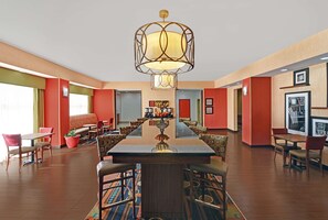 A spacious dining area with a long table, multiple chairs, and a central chandelier.