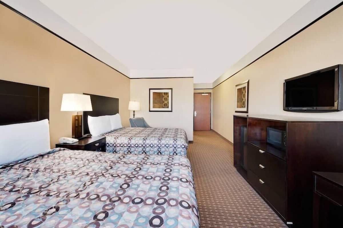 Une chambre d’hôtel avec deux lits, une télévision, un bureau et une armoire.