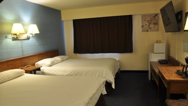A hotel room with two beds, a desk, a chair, a TV, and a small refrigerator. - Canadas Best Value Inn Mile 0 (Lillooet)